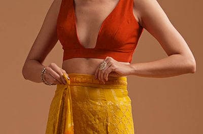 Pleats being tucked at the waist of a yellow silk saree